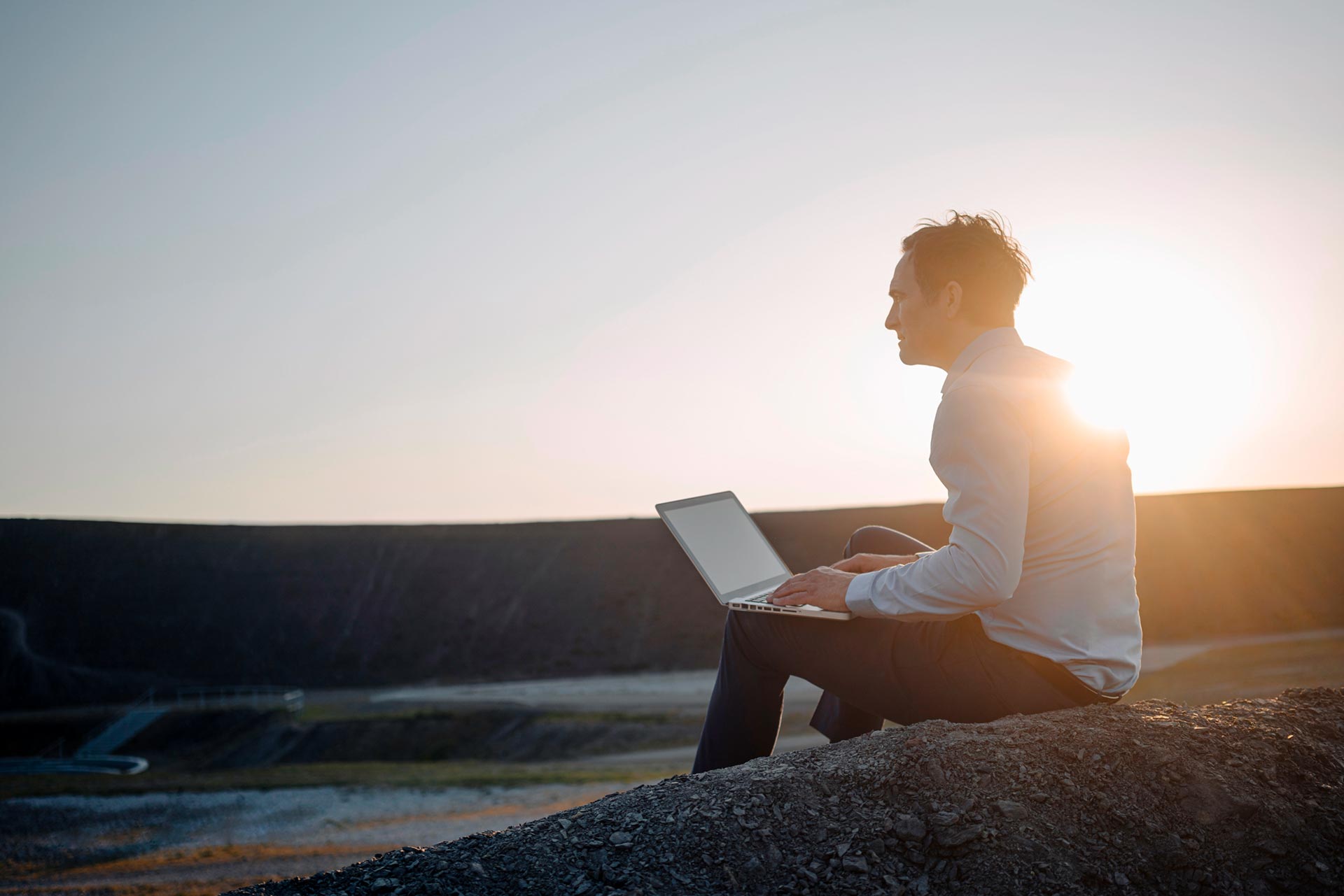 un empresario con un portátil mira la puesta de sol
