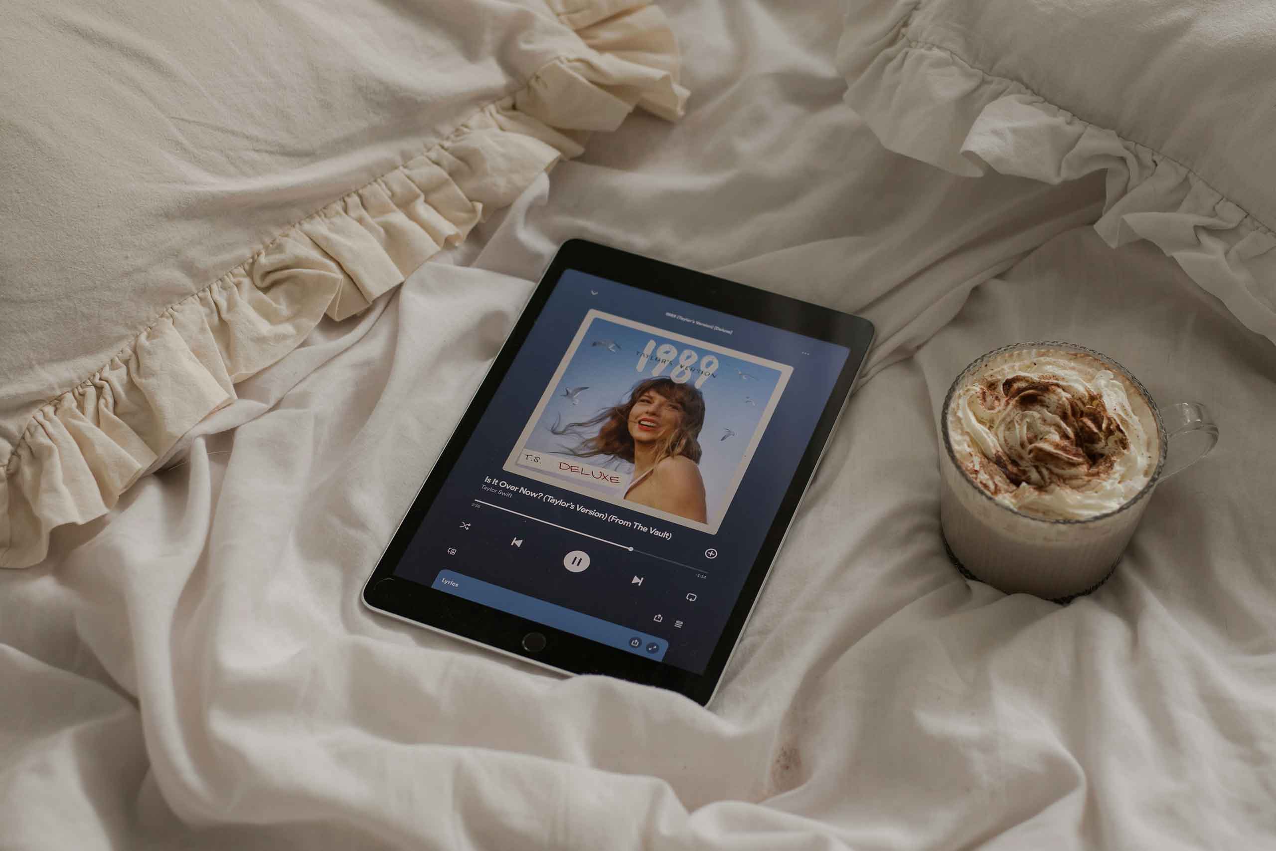 tablet reproduciendo 1989 taylor's versión sobre una cama